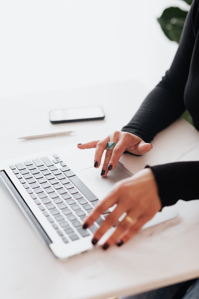 why-choose-us A businesswomans hands typing on a laptop at a bright, modern workspace.